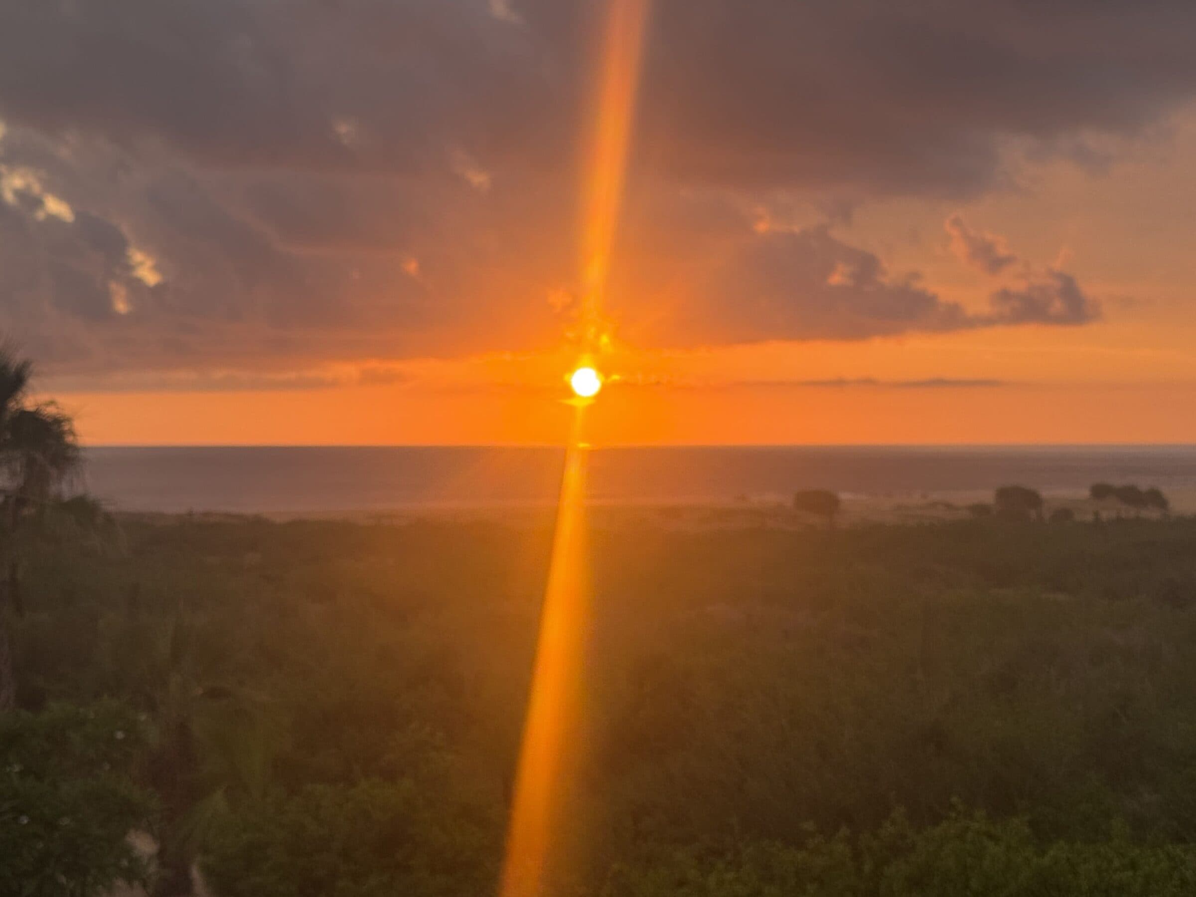 A shaft of sunset light over the dunes and the Pacific